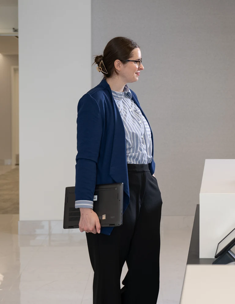 Woman walking through office with laptop