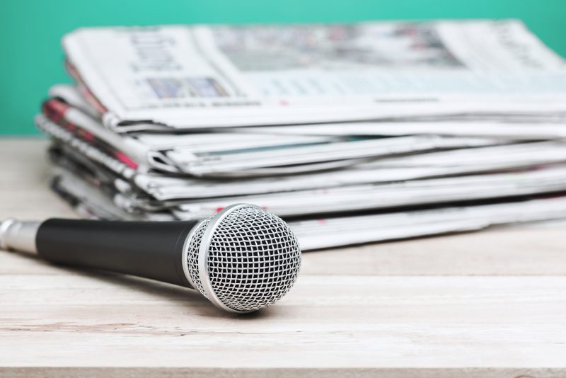 Microphone,With,Newspaper,On,Wooden,Table,-,Announcement,Concept